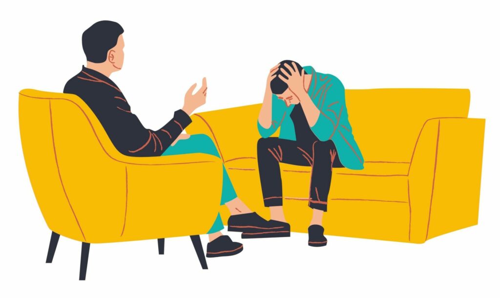 Une personne assise, la tête baissée, montre des signes d’épuisement sur un canapé, tandis qu’une autre personne l’écoute attentivement. L’image illustre la vulnérabilité et la nécessité d’accueillir les signaux de son corps pour se protéger et se régénérer.