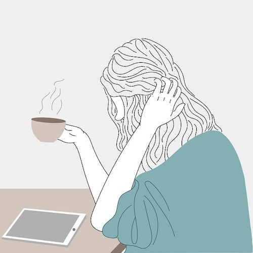 Femme assise, regard fatigué, devant une tasse de café, symbolisant la fatigue et l’épuisement liés à la fibromyalgie